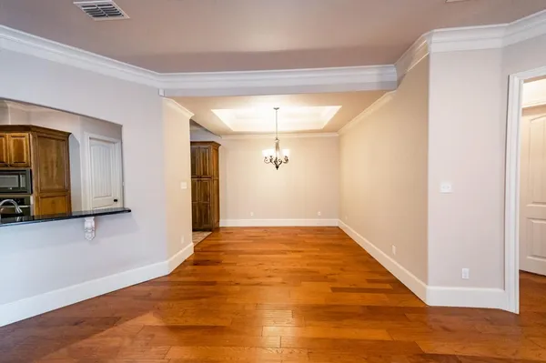 a view of a livingroom with wooden floor and a kitchen