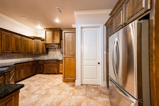 a kitchen with granite countertop a refrigerator and cabinets