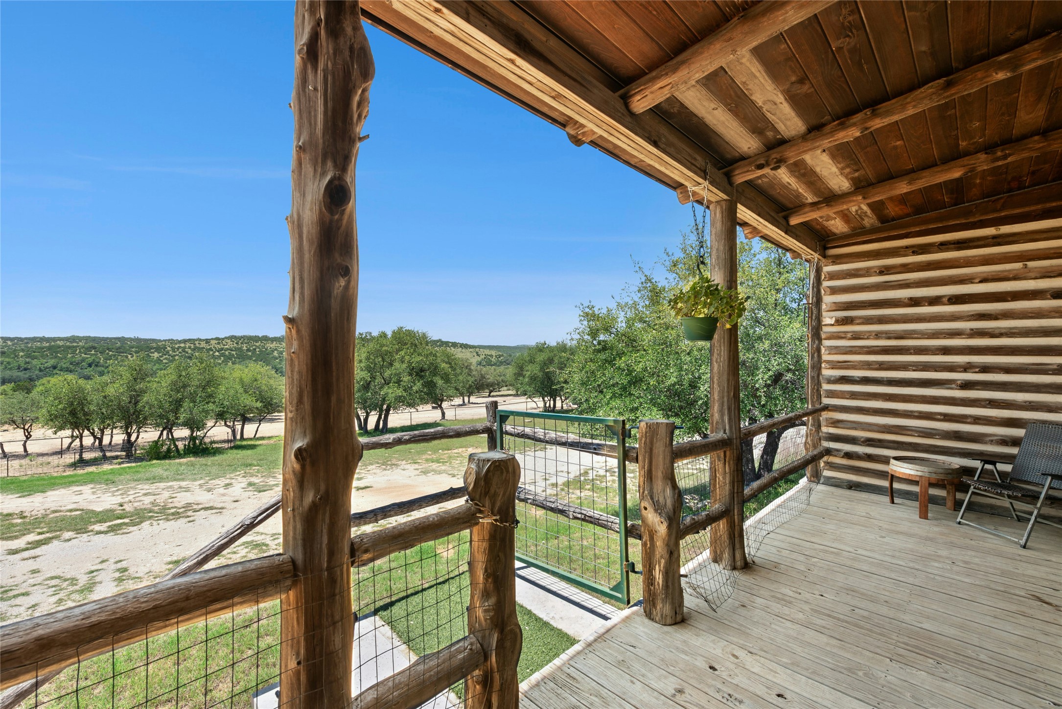496 Middleton Road Spicewood, TX 78669 - Photo 6 of 40 Expansive wooden porch featuring a log cabin exterior, exposed wood beam ceiling, and a rustic log railing with metal mesh
