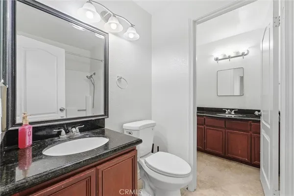 a bathroom with a granite countertop sink toilet and mirror