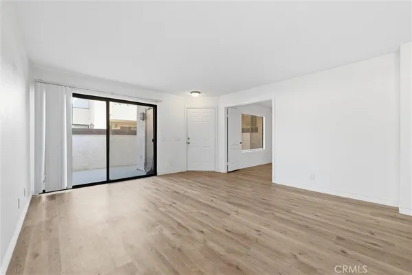 a view of an empty room with wooden floor and windows