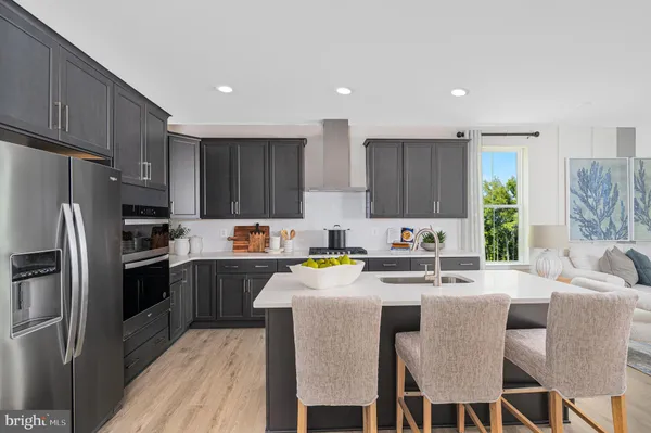 a kitchen with stainless steel appliances granite countertop a stove a sink a refrigerator and a refrigerator with wooden floor