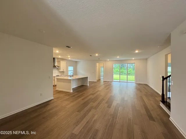 a view of a kitchen with kitchen island wooden floors and stainless steel appliances