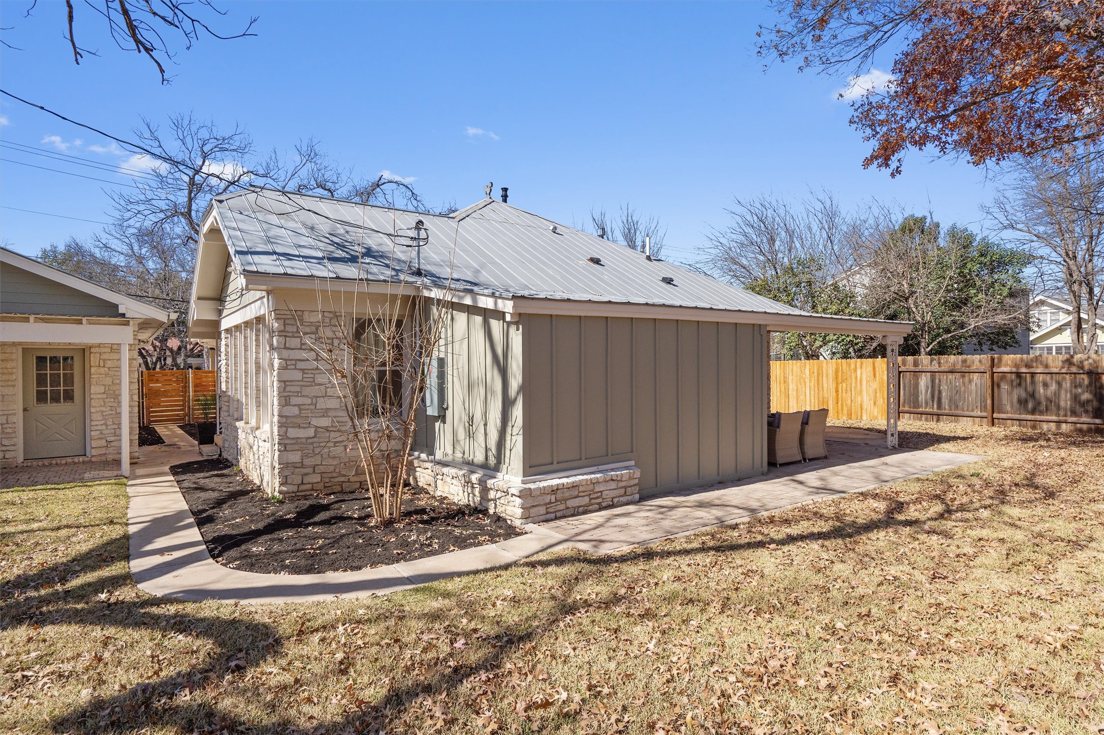 1605 South Austin Avenue Georgetown, TX 78626 - Photo 33 of 40 View of side of home with a fenced backyard, a metal roof, an outdoor structure, and board and batten siding