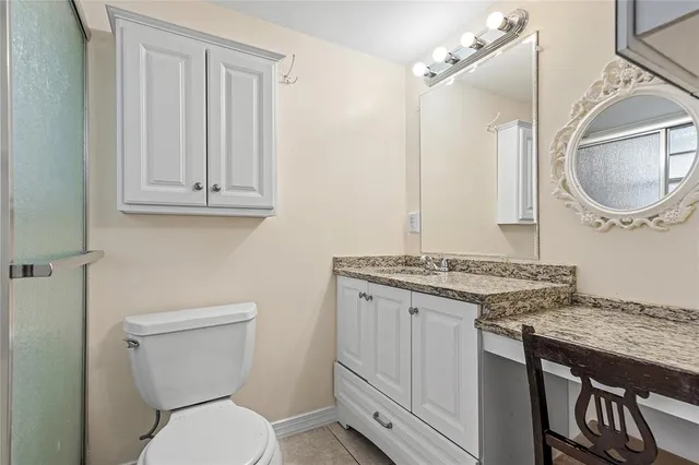 a bathroom with a granite countertop toilet sink and mirror