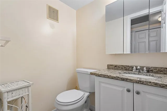 a bathroom with a granite countertop toilet sink and mirror