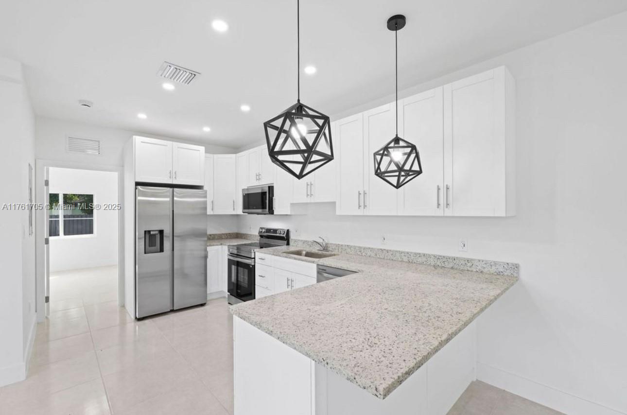 a kitchen with stainless steel appliances granite countertop a sink a stove and a refrigerator
