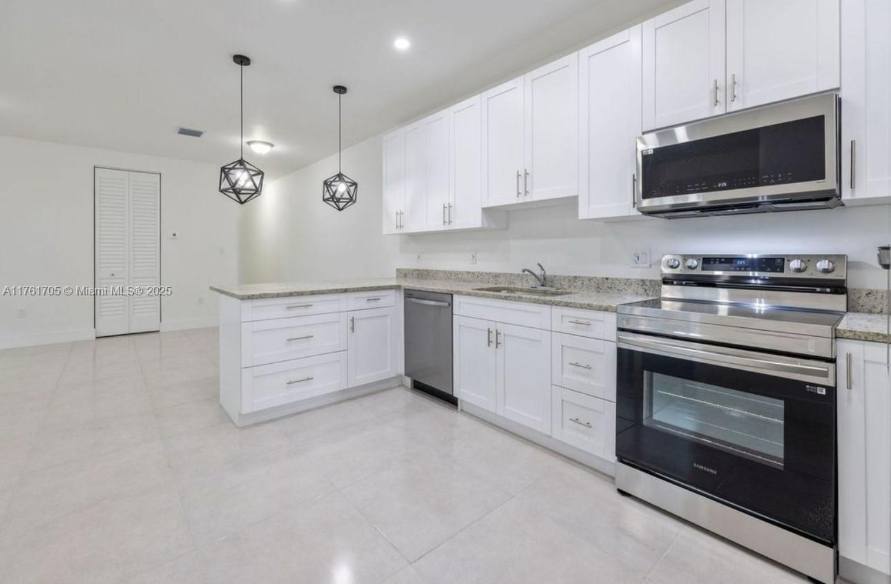 11240 Southwest 187th Street, Unit 11240 Miami, FL 33157 - Photo 2 of 9 a kitchen with stainless steel appliances a stove a sink and a microwave
