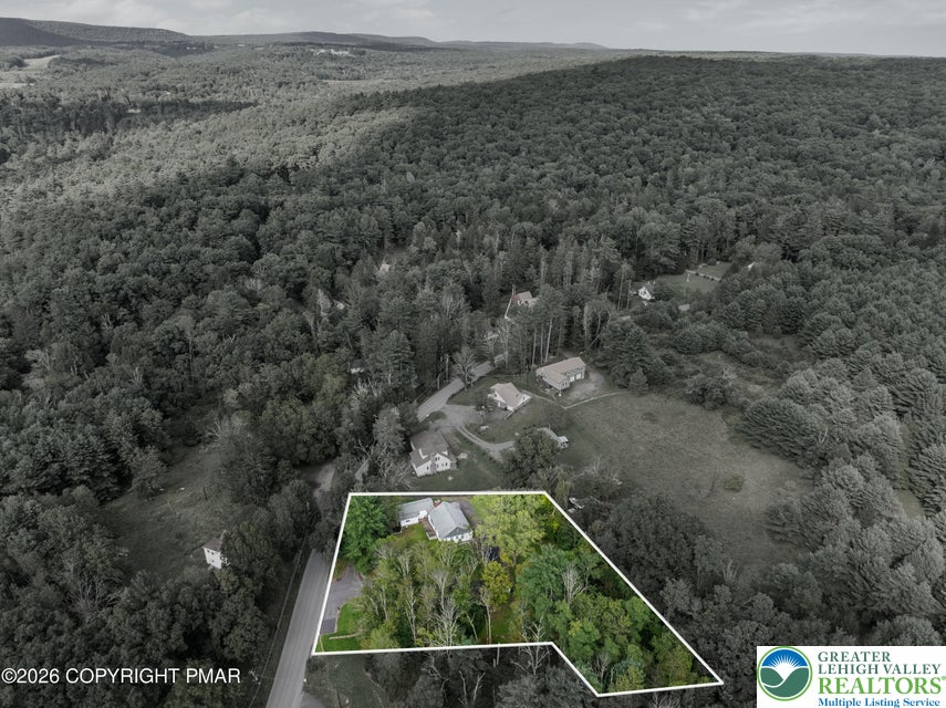 1207 Seese Hill Road Canadensis, PA 18325 - Photo 30 of 49 An aerial view highlights the property nestled within a dense forest and rolling mountain scenery.