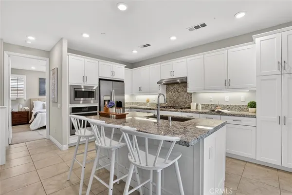 a kitchen with stainless steel appliances granite countertop a stove top oven a sink refrigerator and cabinets
