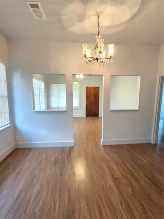 an empty room with wooden floor chandelier and entryway