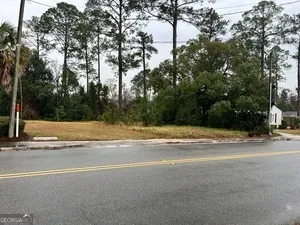 a view of a house with a yard and large trees