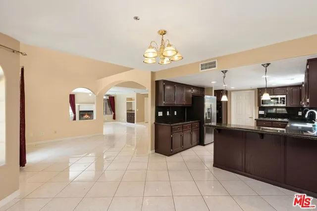 a kitchen with granite countertop a refrigerator a stove top oven and a sink