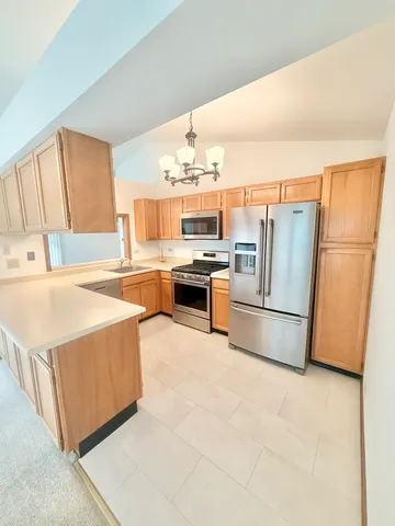 a kitchen with stainless steel appliances a refrigerator a stove a sink a dining table and chairs