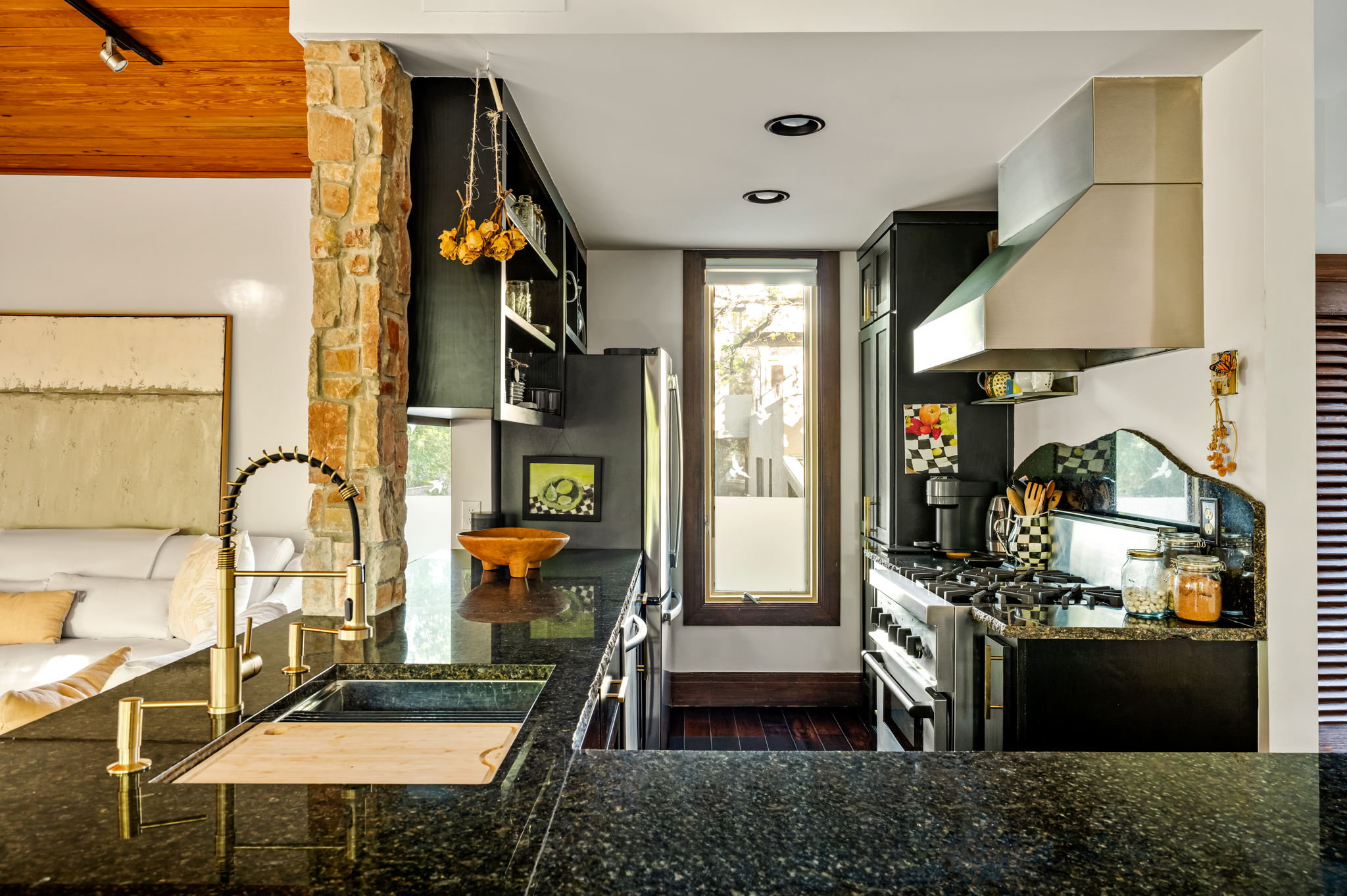 1111 West 12th Street, Unit 107 Austin, TX 78703 - Photo 16 of 38 Gourmet kitchen featuring dark cabinetry, speckled countertops, a stainless steel range hood, a gold-tone pull-down faucet, and recessed lighting