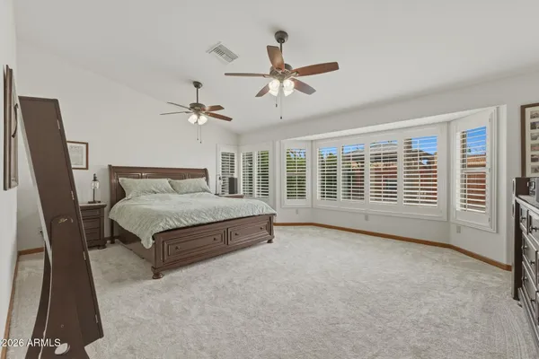 a spacious bedroom with a bed a flat screen tv and a chandelier