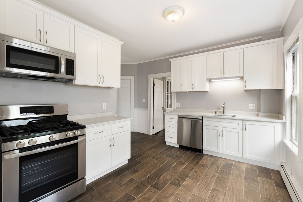 48 Rice Street, Unit 1 Cambridge, MA 02140 - Photo 4 of 16 a kitchen with granite countertop white cabinets stainless steel appliances and sink