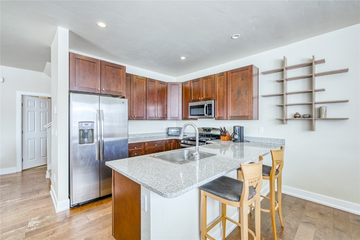 29 Haymaker Street, Unit 2B Silverthorne, CO 80498 - Photo 22 of 28 Kitchen with open shelves, stainless steel appliances, a sink, light wood-style flooring, and a peninsula