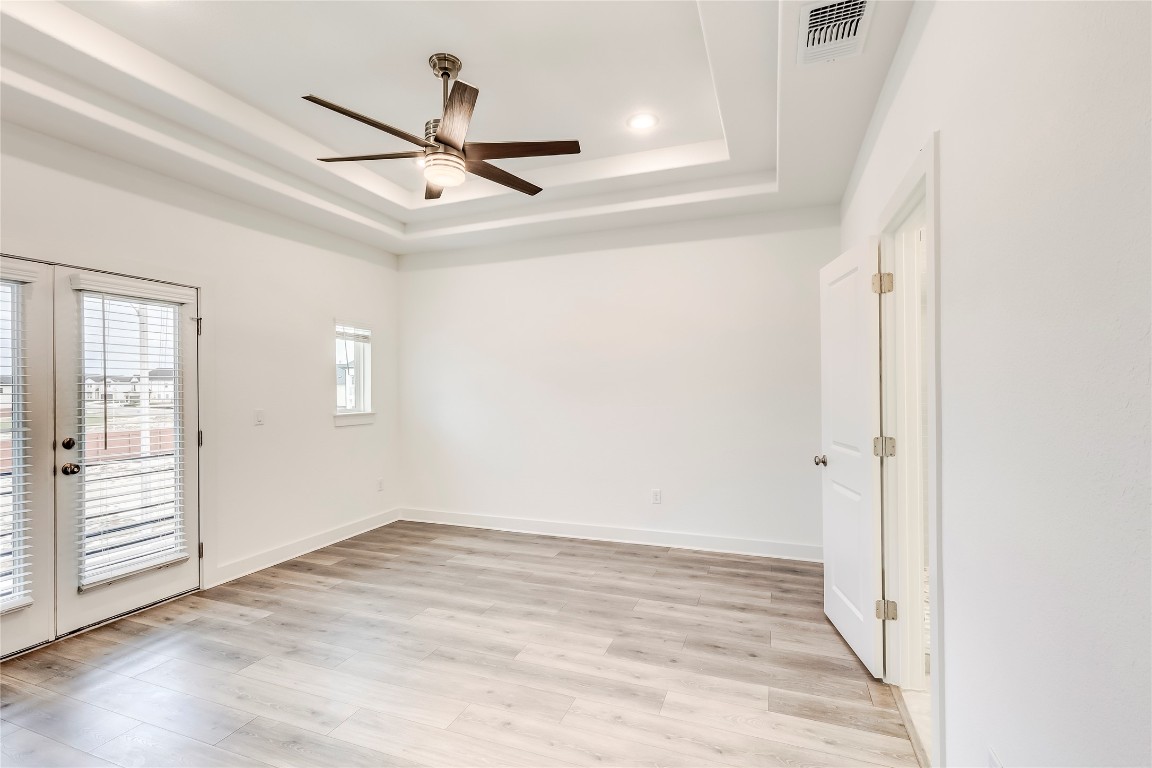 2000 Kit Circle Austin, TX 78758 - Photo 18 of 34 Unfurnished room featuring french doors, light wood-style flooring, a tray ceiling, a ceiling fan, and recessed lighting