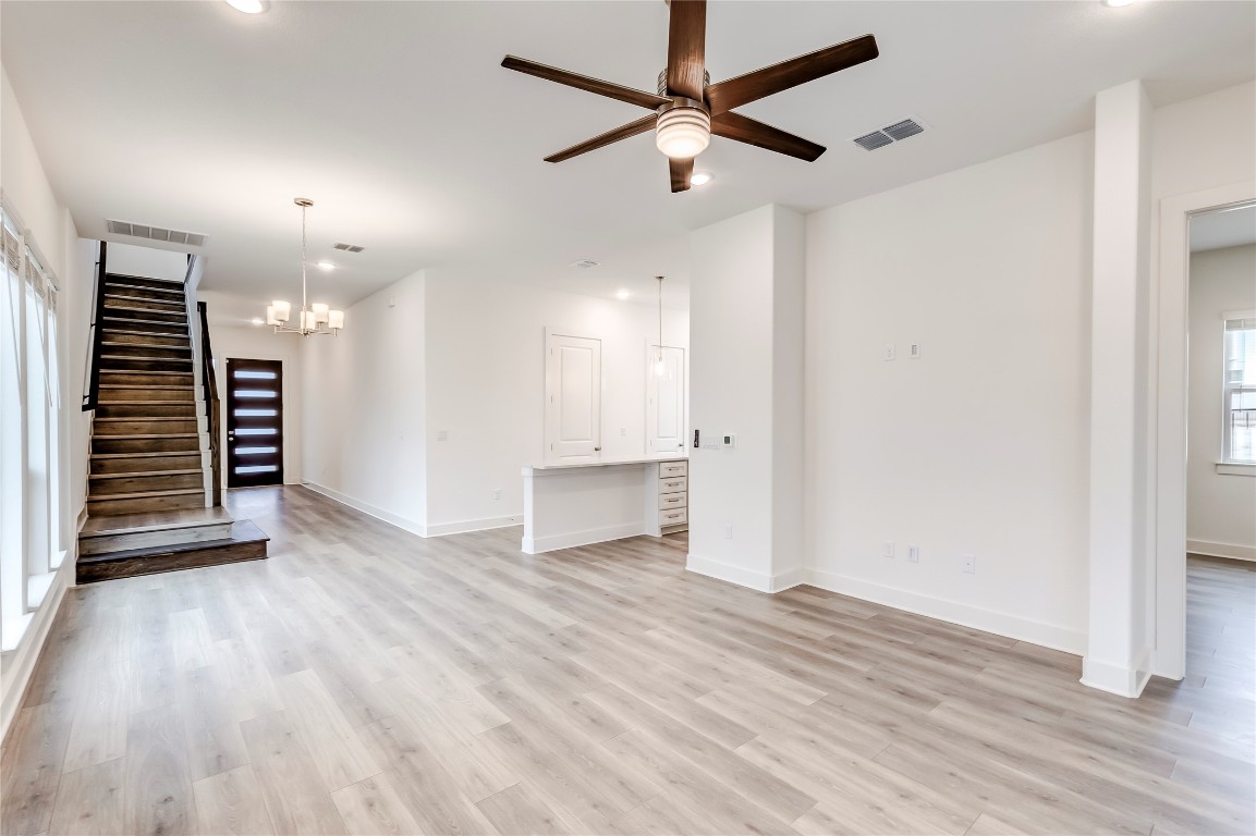 2000 Kit Circle Austin, TX 78758 - Photo 6 of 34 Unfurnished living room with a chandelier, light wood-type flooring, a ceiling fan, recessed lighting, and stairway