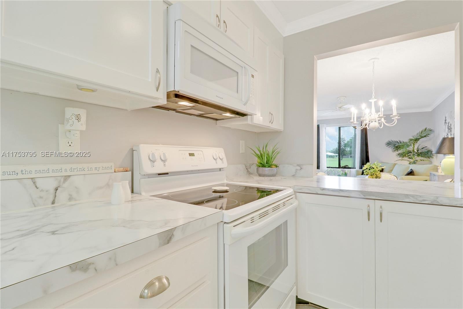 5313 Southeast Miles Grant Road, Unit 206 Stuart, FL 34997 - Photo 8 of 39 a kitchen with kitchen island white cabinets and white appliances
