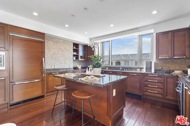 a kitchen with stainless steel appliances granite countertop a refrigerator a sink dishwasher a stove with wooden cabinets and wooden floor