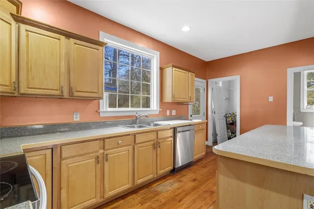 a kitchen with stainless steel appliances granite countertop a sink and cabinets with wooden floor