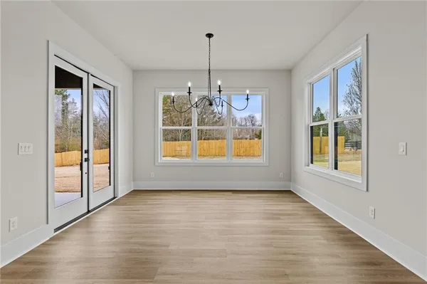 a view of an empty room with window and wooden floor