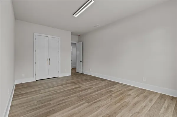 a view of an empty room with wooden floor and closet