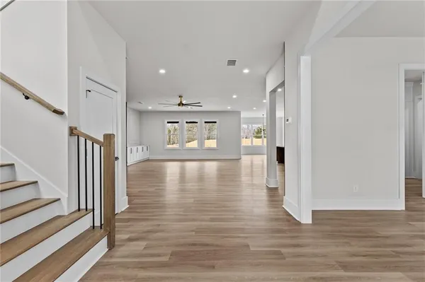 a view of a hallway with wooden floor and a kitchen space