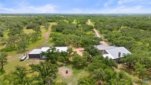an aerial view of residential house with outdoor space and trees all around