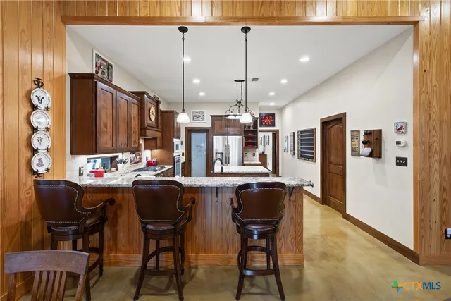 a kitchen with stainless steel appliances kitchen island granite countertop a table chairs and a refrigerator