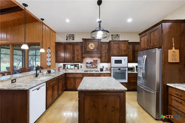 a large kitchen with a large island in the center a sink stainless steel appliances and a counter top space