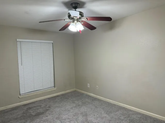 en empty room with window and chandelier fan