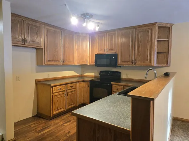 a kitchen with stainless steel appliances granite countertop wooden cabinets a stove a sink and a microwave
