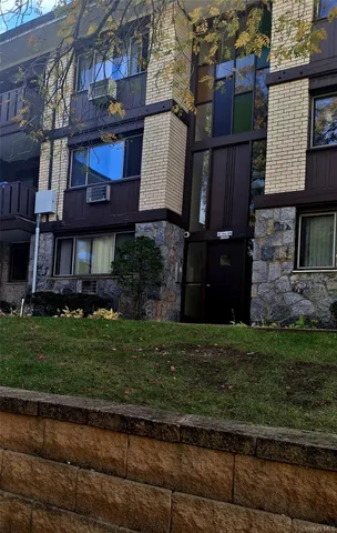 a view of a brick house with a yard and plants
