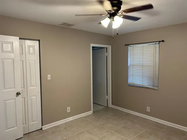 a view of an empty room with a ceiling fan and a window