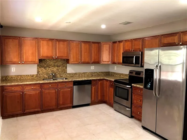 a kitchen with granite countertop wooden cabinets a stove top oven a sink and dishwasher