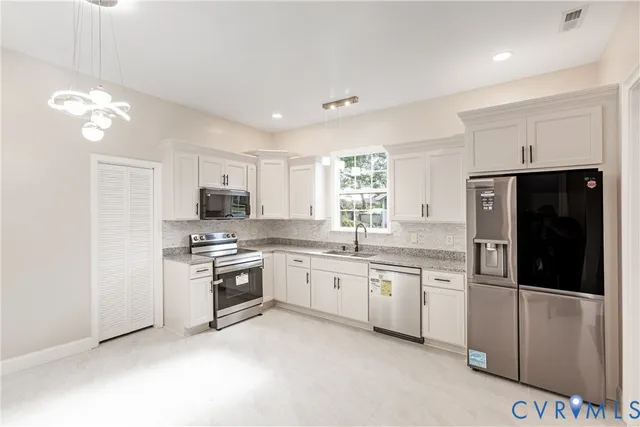 a kitchen with stainless steel appliances a stove a sink a refrigerator and a cabinets