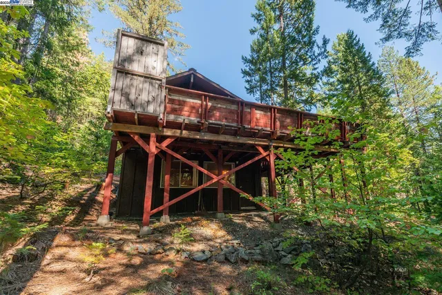 a view of a wooden house with a yard and seating space