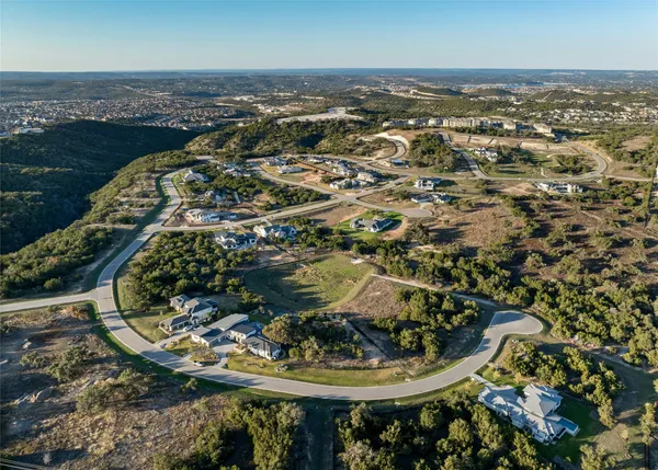 an aerial view of a residential houses with outdoor space and trees