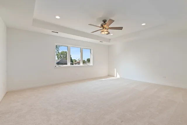 an empty room with windows and ceiling fan