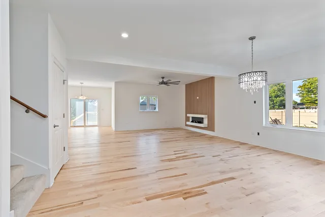 a view of an empty room with window and wooden floor