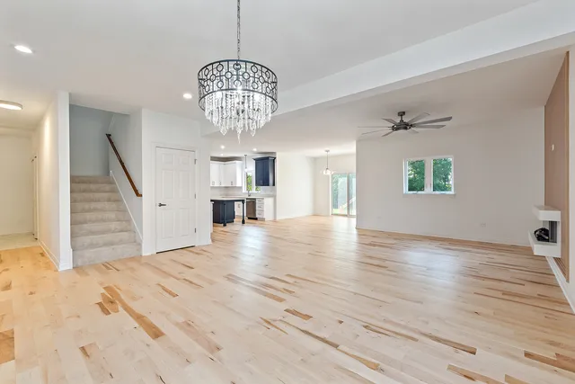 a view of an empty room with wooden floor and staircase