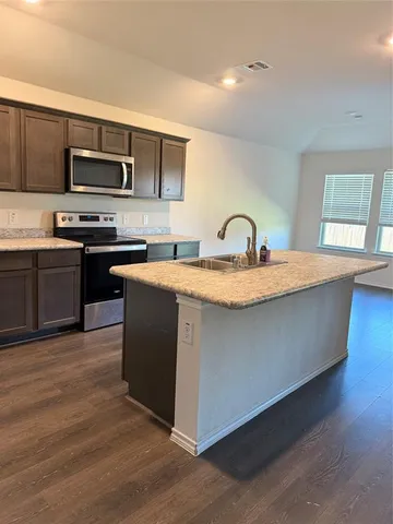 a kitchen with stainless steel appliances granite countertop a sink a stove top oven and wooden floors