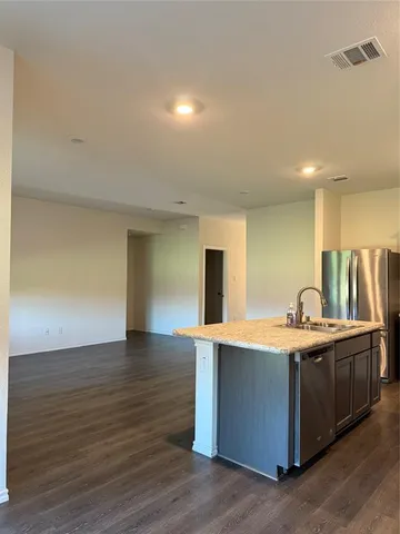 a view of a kitchen with kitchen island a sink wooden floor and a counter top space