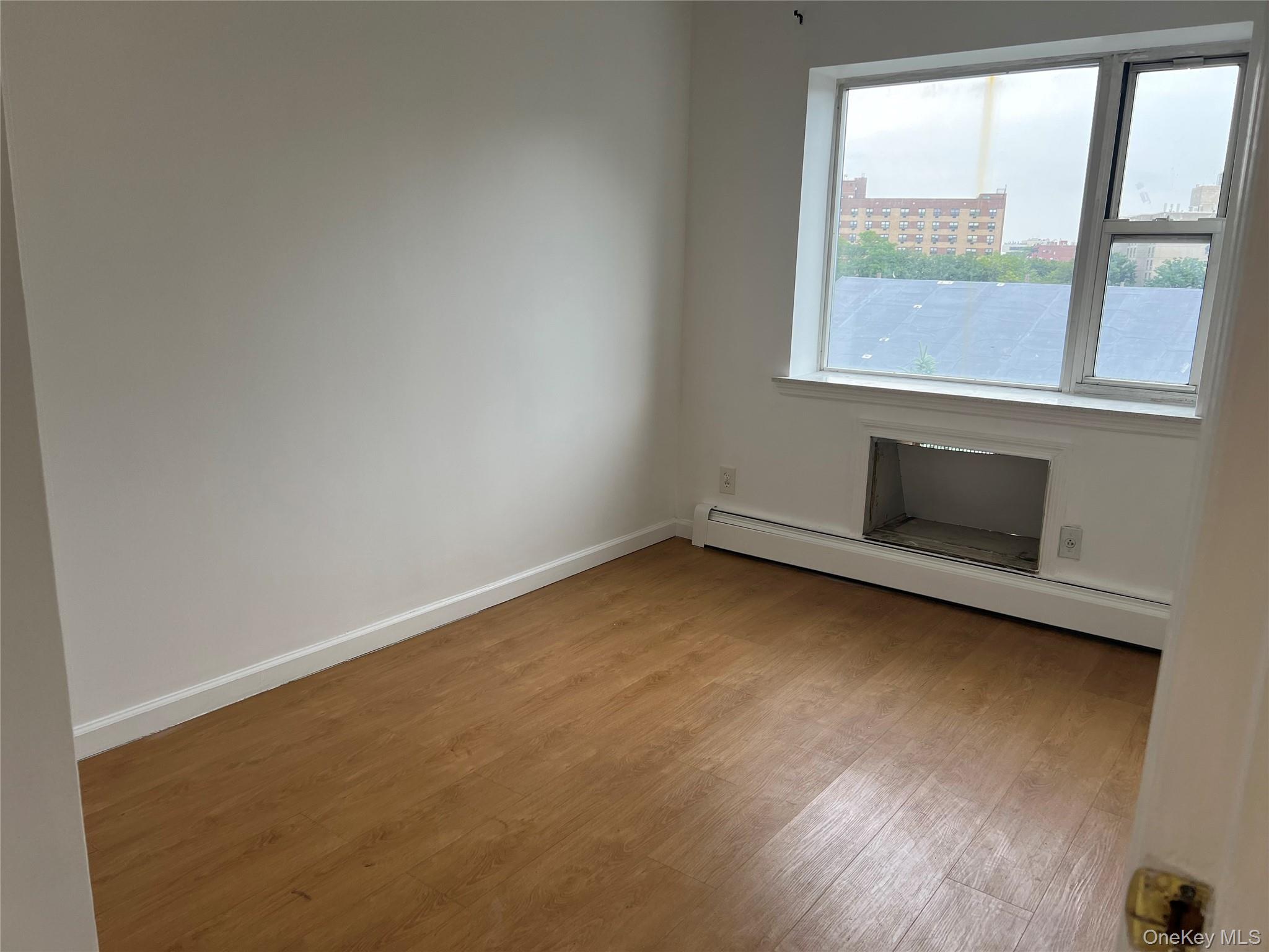 55-05 98th Street Queens, NY 11368 - Photo 3 of 12 Empty room featuring wood finished floors, baseboard heating, and baseboards