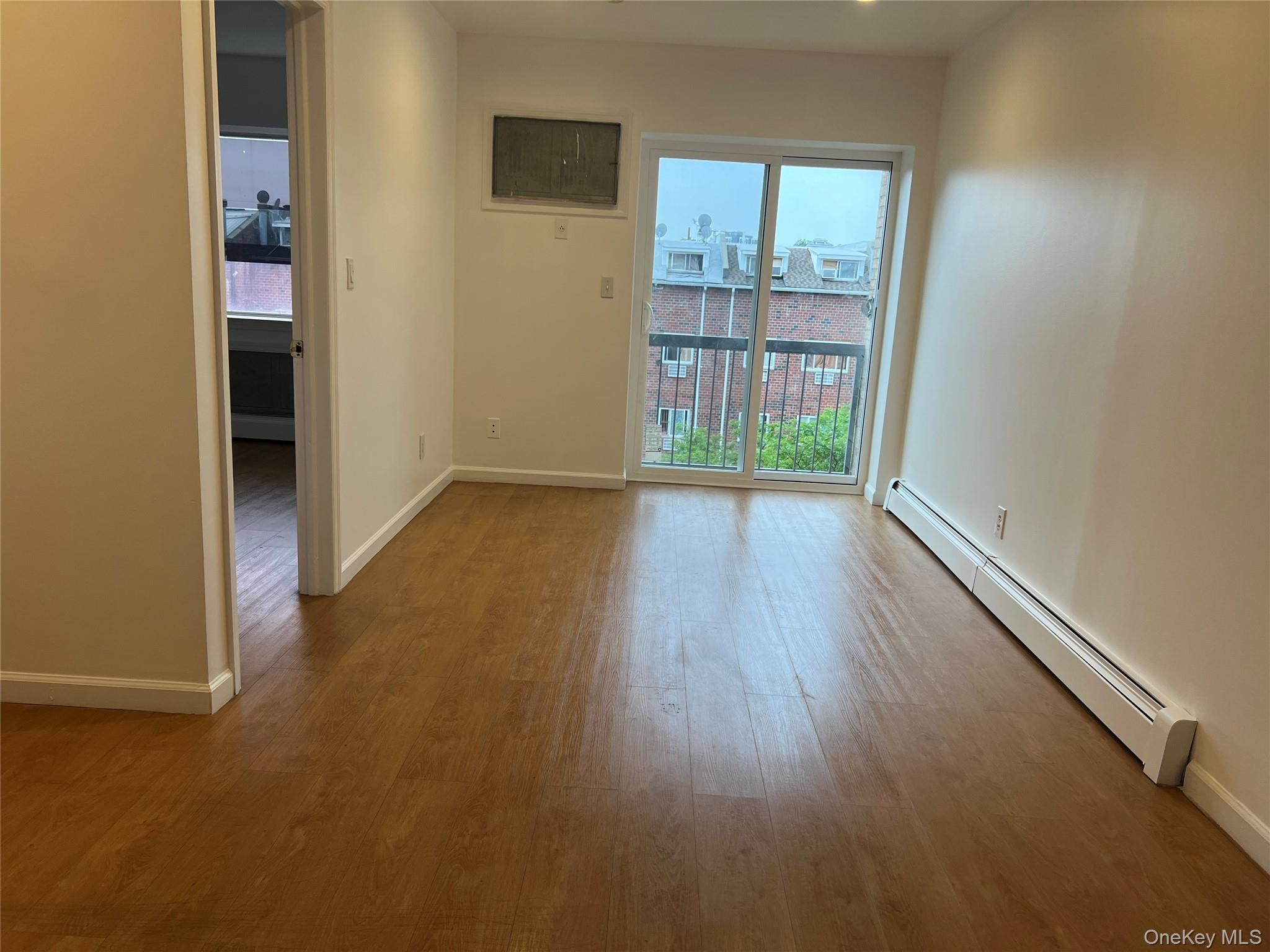 55-05 98th Street Queens, NY 11368 - Photo 6 of 12 Unfurnished room with a baseboard radiator, plenty of natural light, wood finished floors, and baseboards