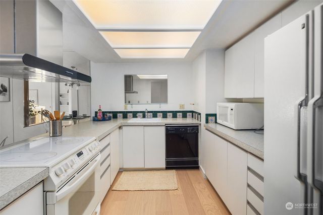 a kitchen with granite countertop a sink stainless steel appliances and white cabinets