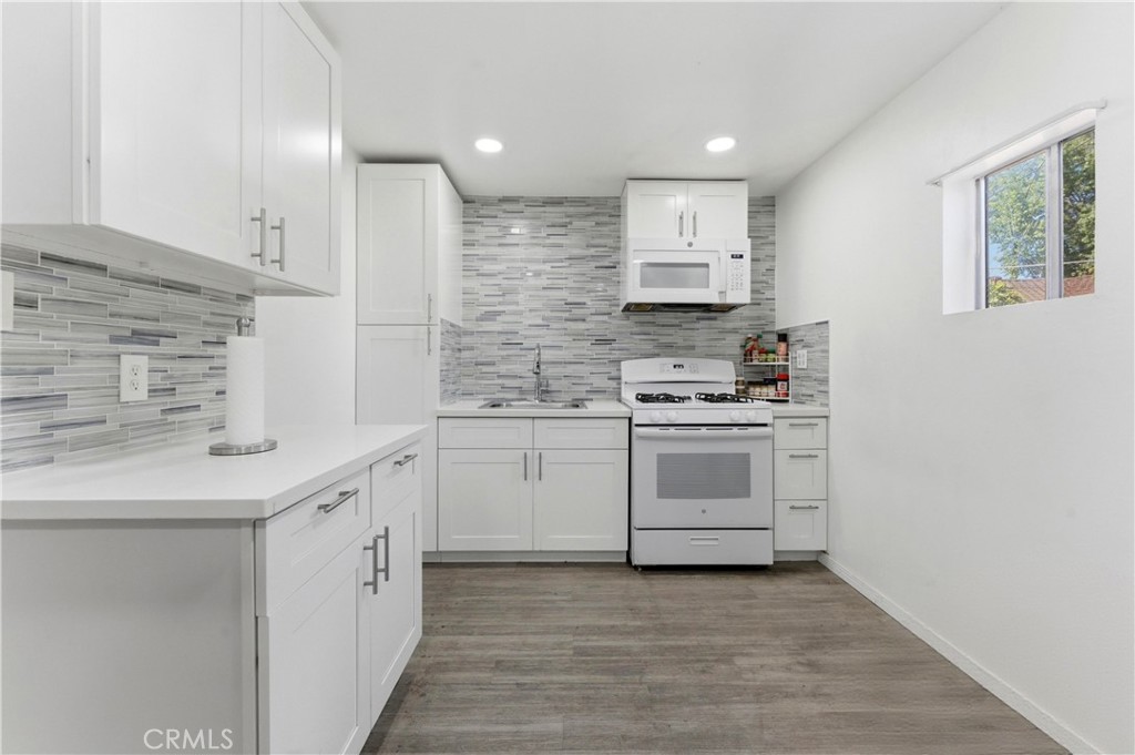 121 East 68th Way Long Beach, CA 90805 - Photo 13 of 17 a kitchen with white cabinets and white appliances